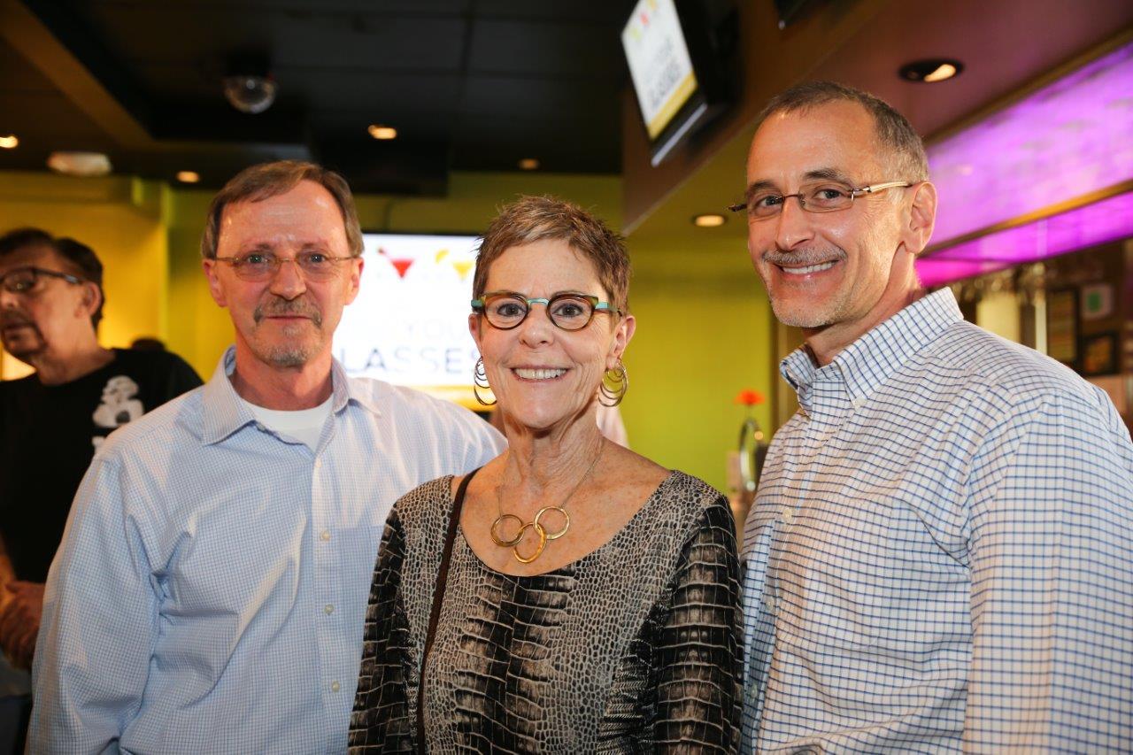 Three guests standing inside and smiling at Raise Your Glasses event