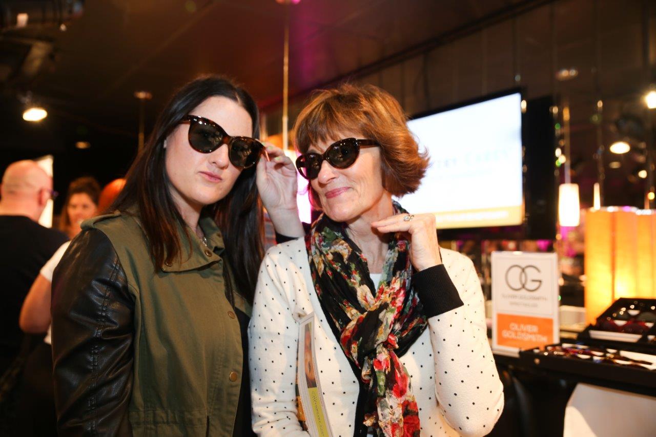 Two women posing in sunglasses at Raise Your Glasses event