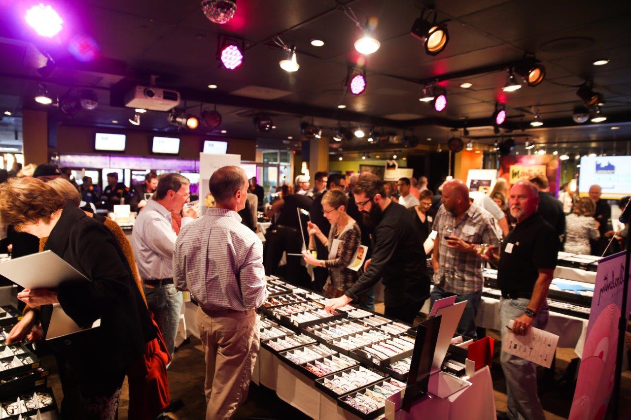 Many people standing inside and looking at framelines at Raise Your Glasses event