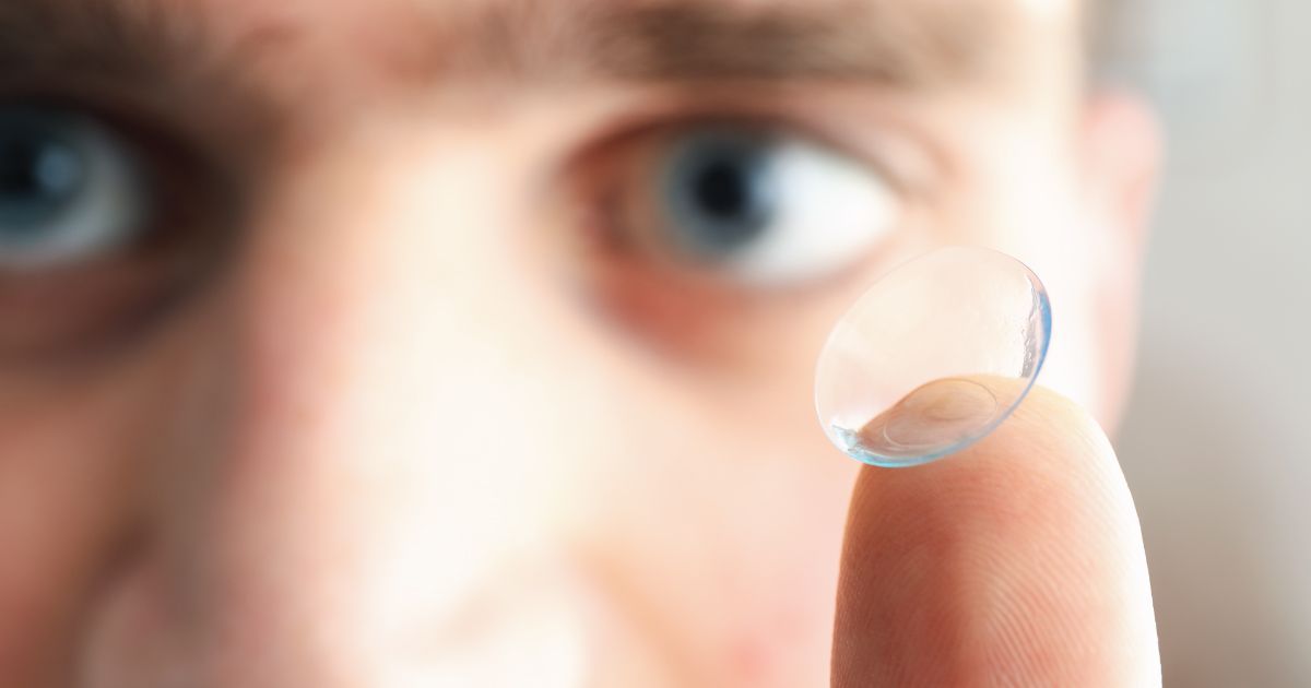 Close-up of a person holding a clear contact lens near their eye