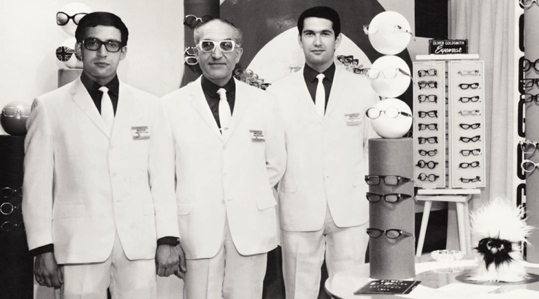1960's vintage image of Oliver Goldsmith standing with two other men inside his optical shop