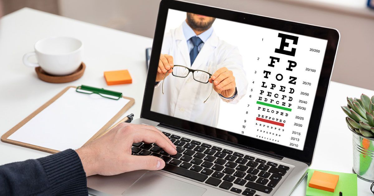 A person is using a laptop computer with an eye chart on the screen.