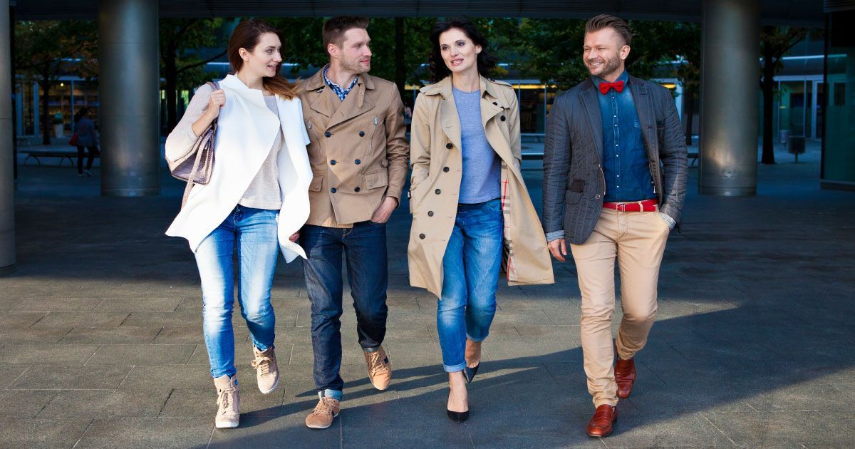 A group of well-dressed people are walking down a sidewalk.