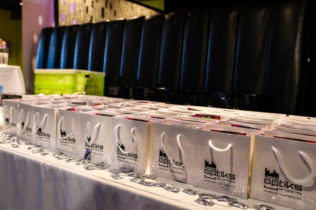 Small shopping bags with Urban Optiks Optometry logo on them at 2015 Raise Your Glasses event