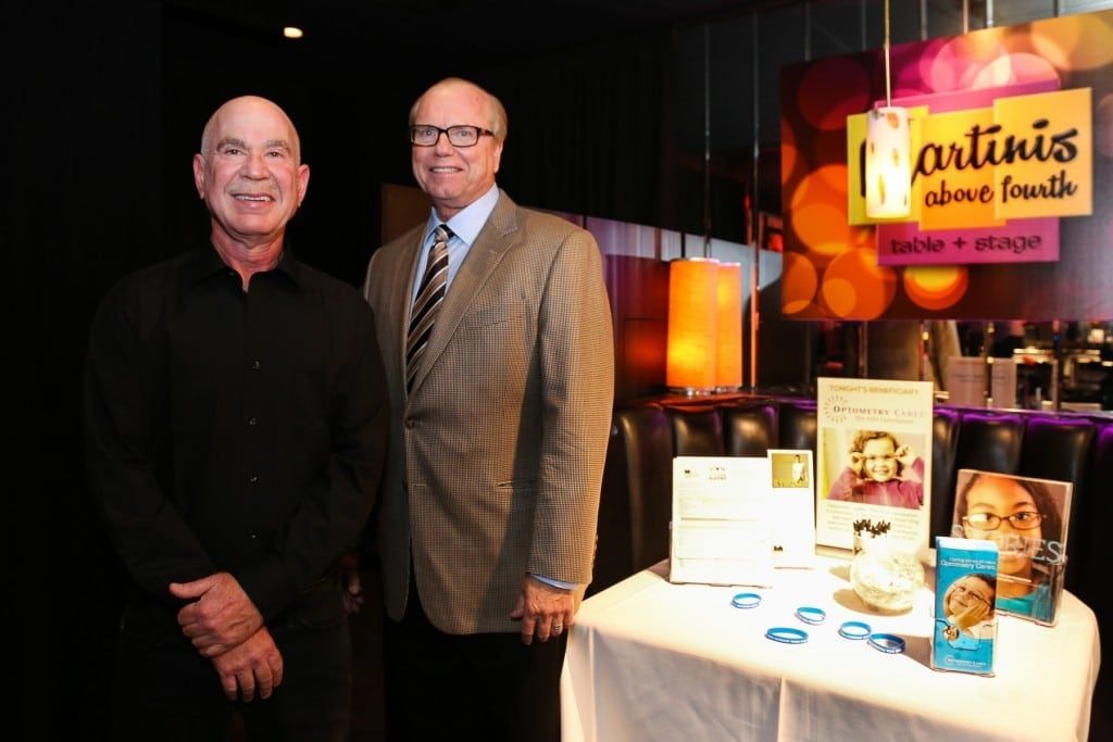 Two people standing next to vendor table at 2015 Raise Your Glasses event