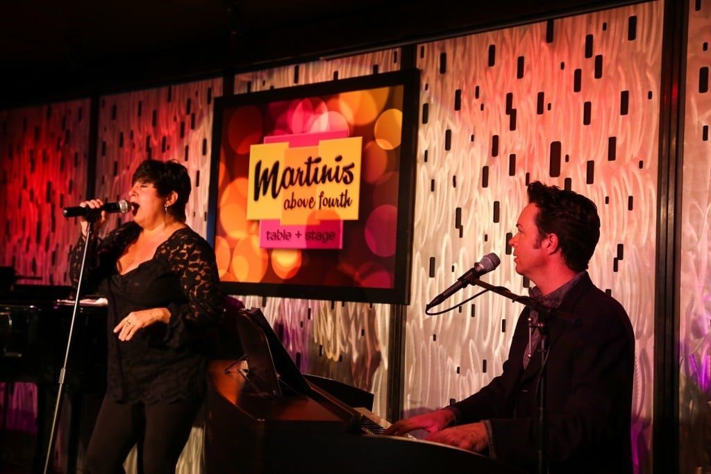 Two people onstage performing at 2015 Raise Your Glasses event