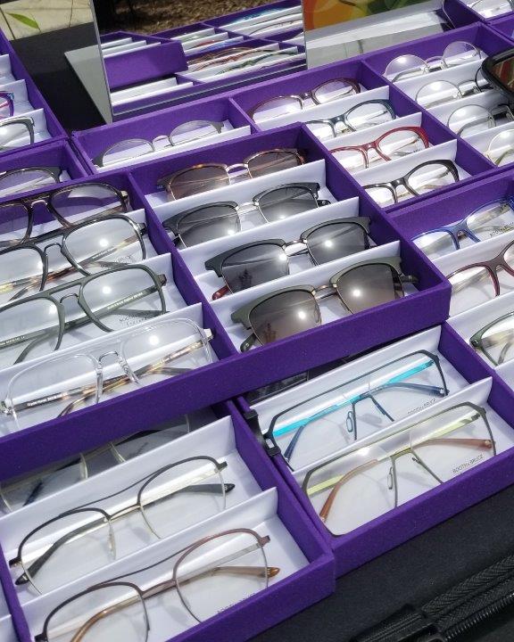 Many purple display boxes of assorted eyeglasses and sunglasses at 2019 Raise Your Glasses Event
