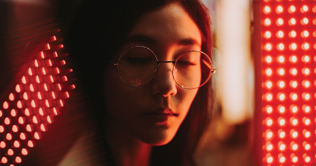 Close-up of a person with glasses in red LED lights , looking down thoughtfully