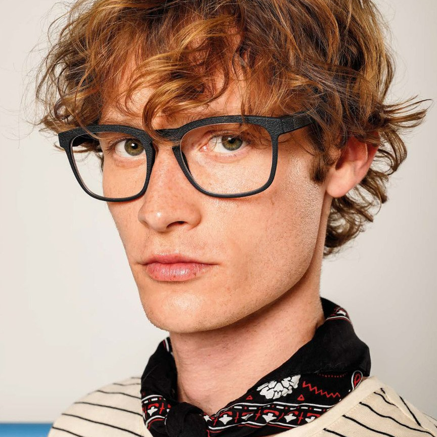 Man wearing a scarf around his neck and a pair of gray Rolf spectacles