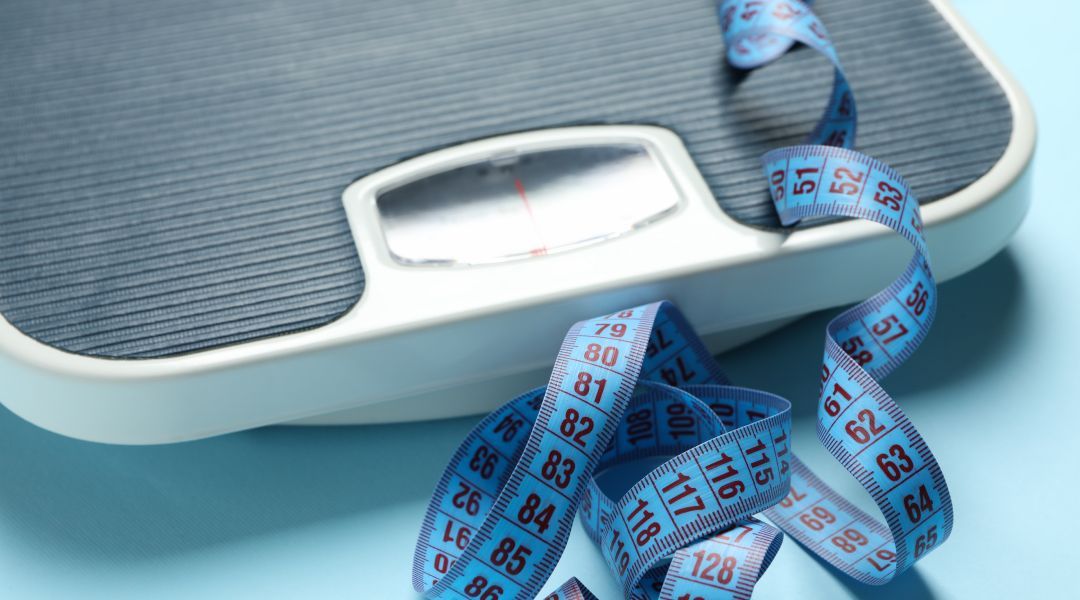 A floor scale with a curled measuring tape on the side