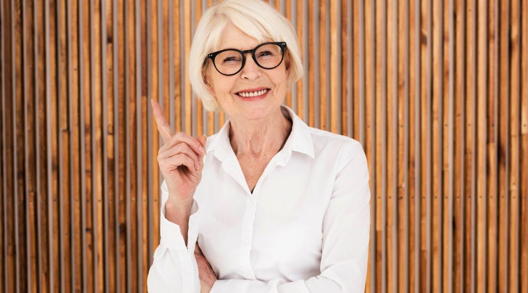 A mature woman wearing glasses with 1 fingure in the air