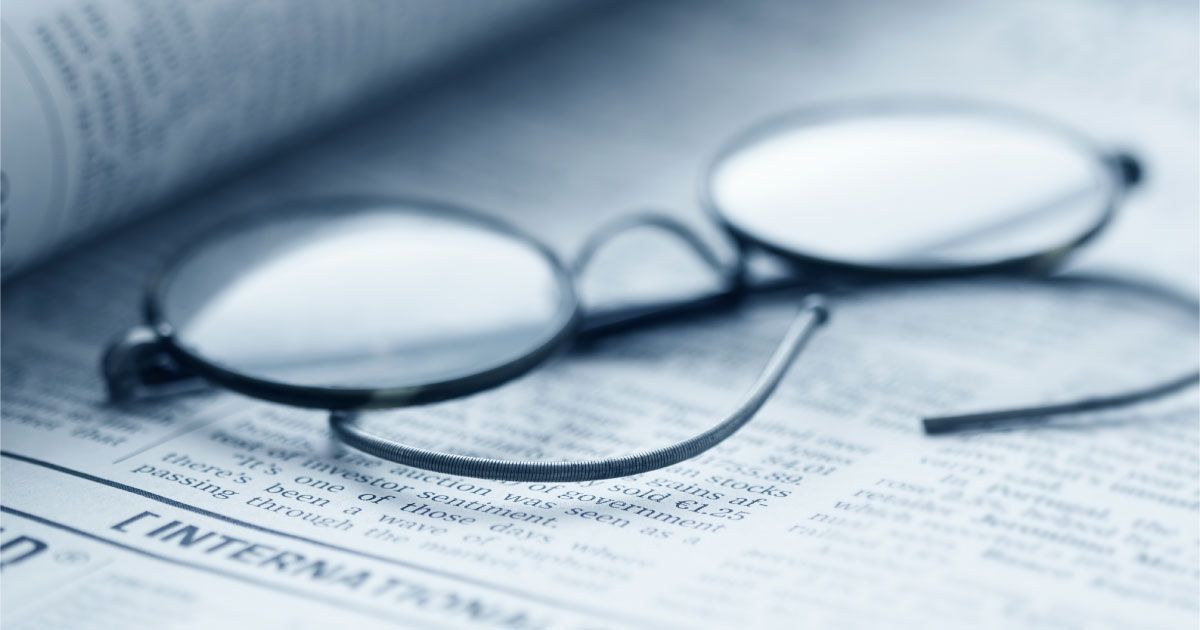 A pair of vintage glasses laying on top of an open newspaper
