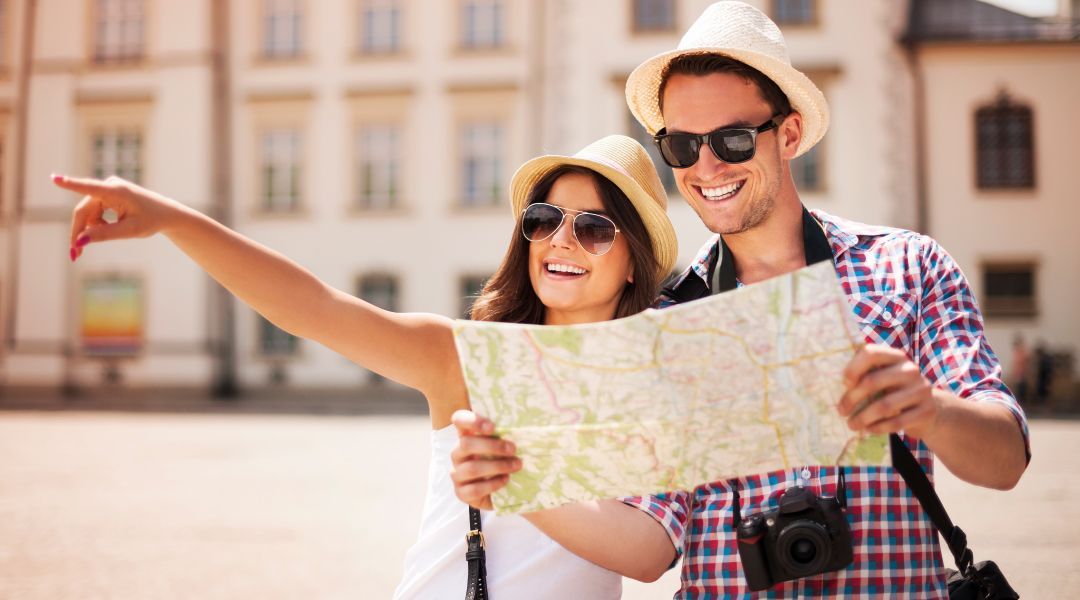 A tourist coouple couple wearing sunglasses looking at a map and pointing to the distance