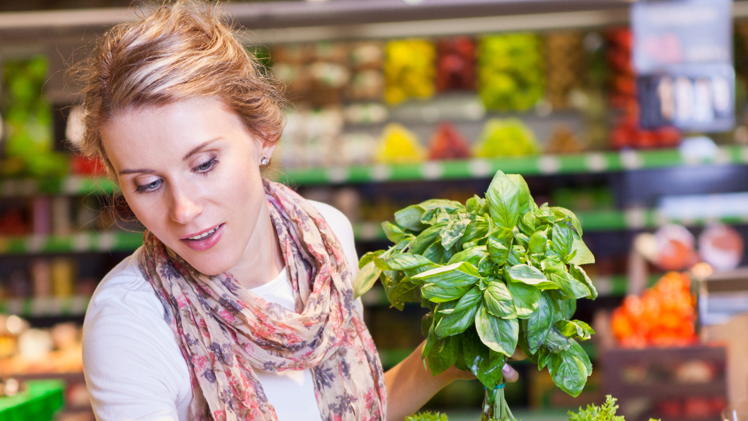 Person in market holding green vegetables