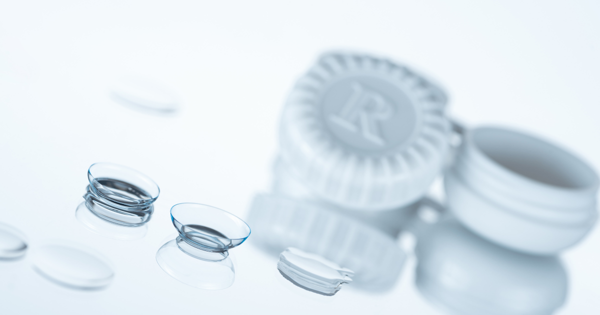 A close up of contact lenses and a case on a white surface