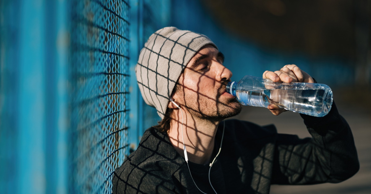 Man in cap and jacket drinking a bottle of water