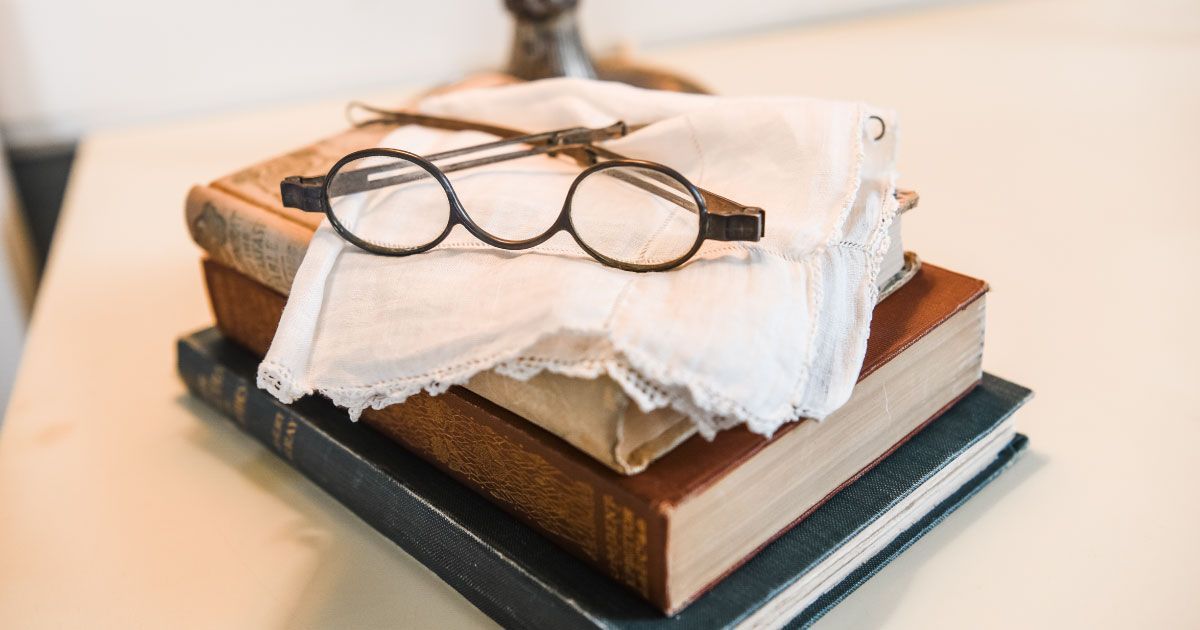 A pair of vintage glasses is sitting on top of a stack of books.