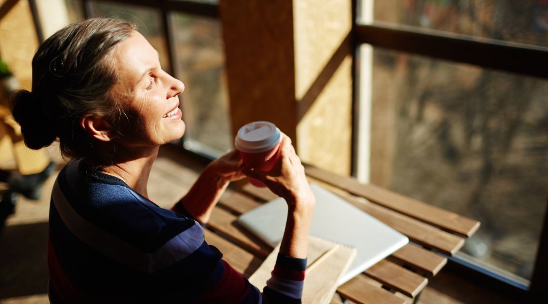 Woman sitting in a window with sunlight shinning on her face