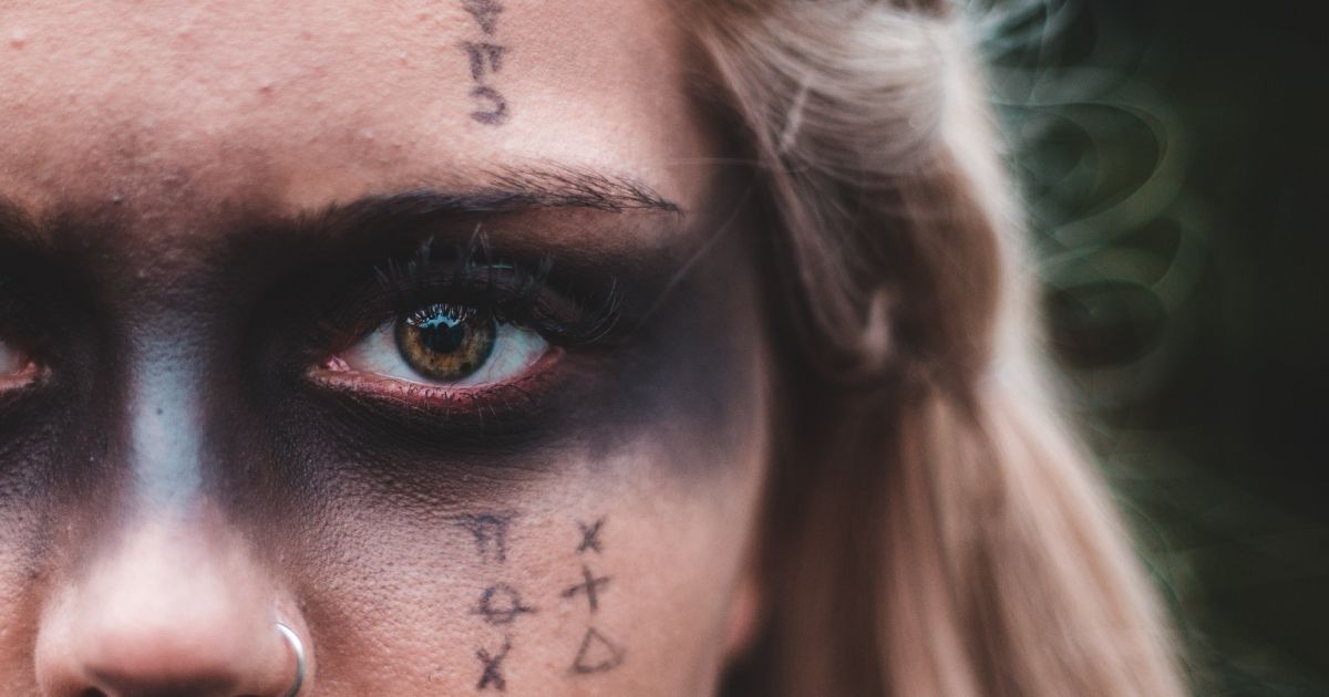 A close up of a woman 's face with black makeup and tattoos on it.