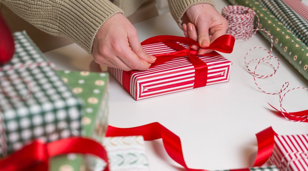 A person wrapping christmas gifts on the table