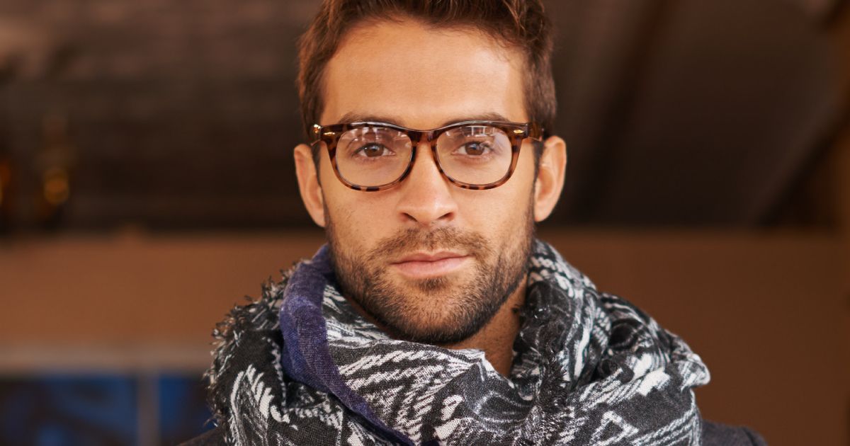 Man wearing glasses and scarf, looking directly at the camera.