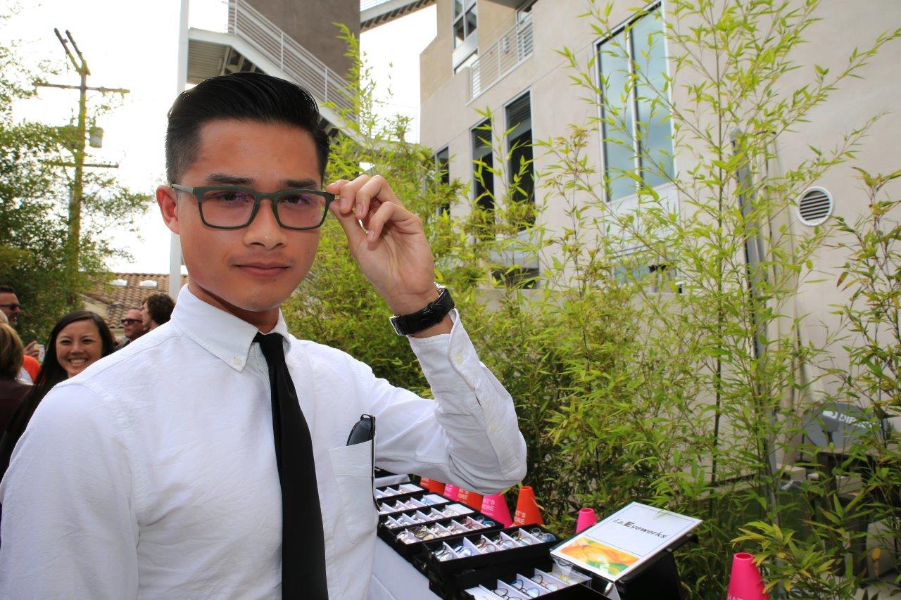 Person in white shirt and tie trying on glasses at Raise Your Glasses 2017 Event