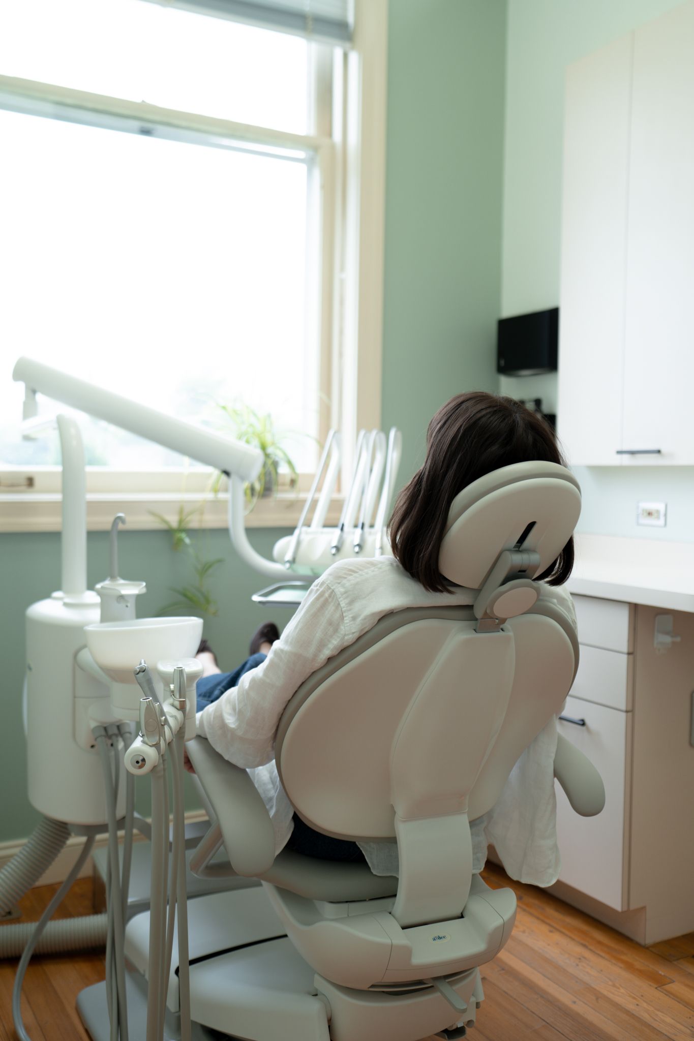 A woman is sitting in a dental chair in a dental office.
