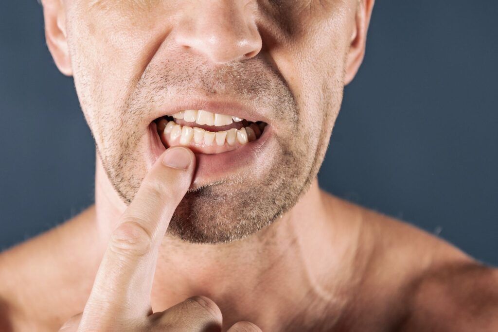 A man without a shirt is holding his finger to his mouth.