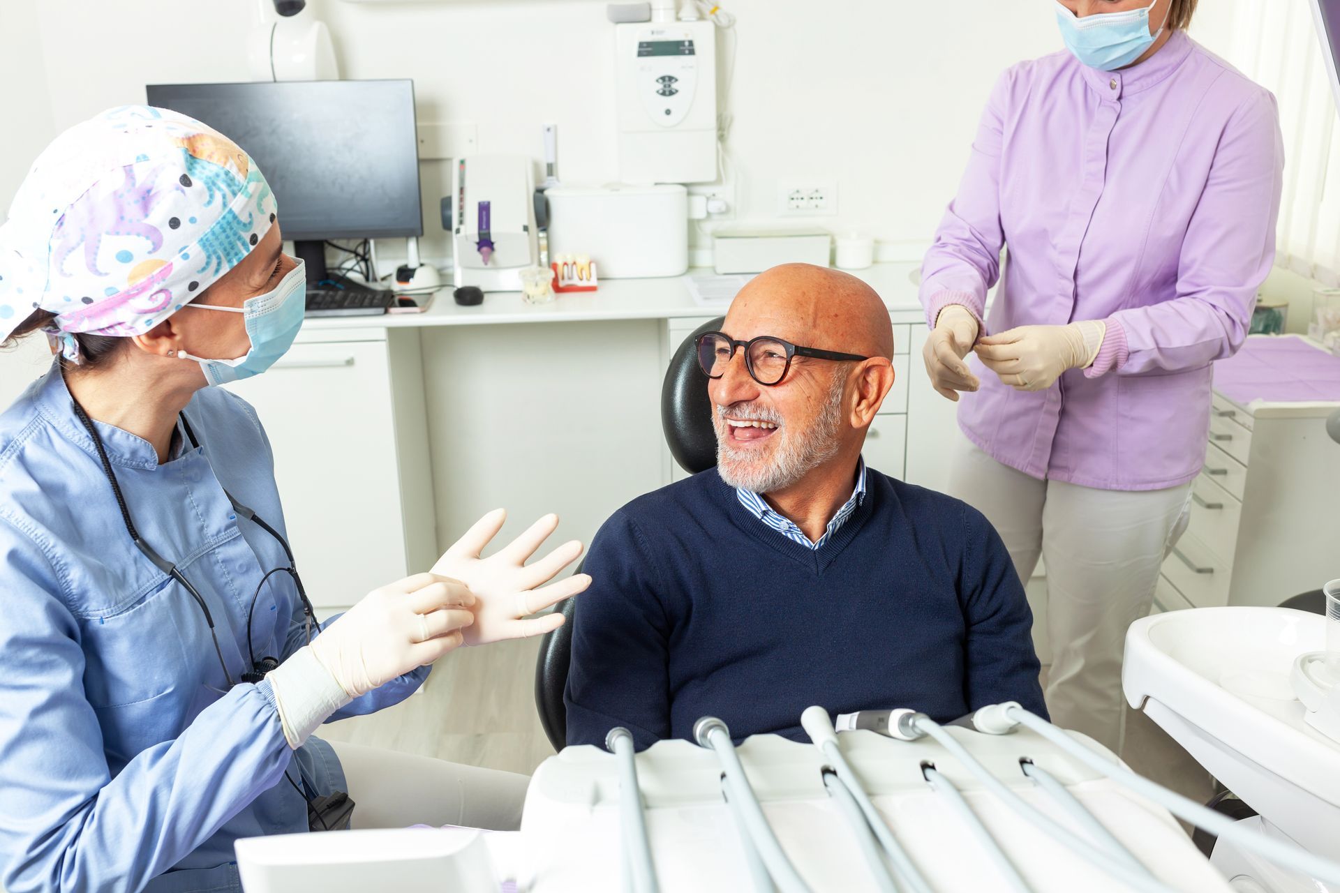 A man is sitting in a dental chair talking to a dentist.