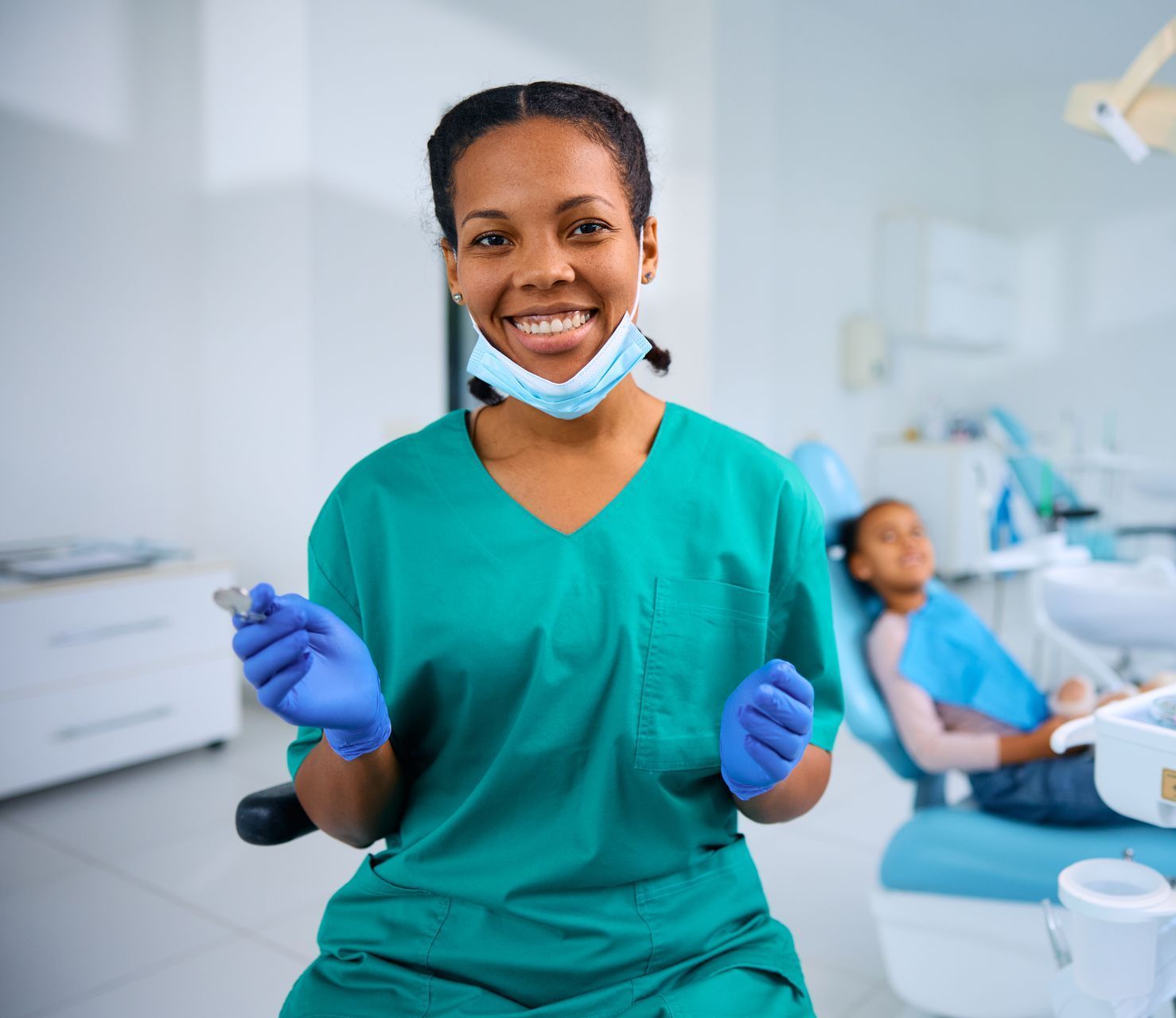A female dentist is smiling while holding a dental tool in a dental office.