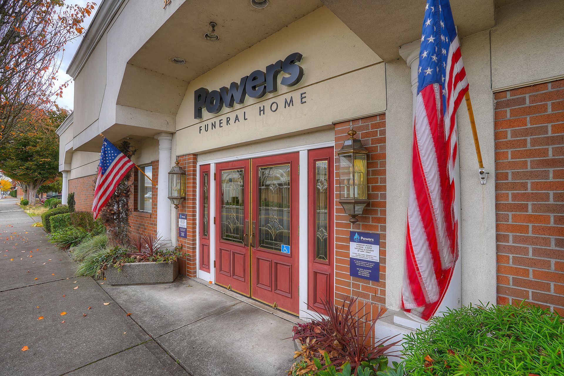 Front entrance of a Power’s Gym, with red doors and large American flags on either side.