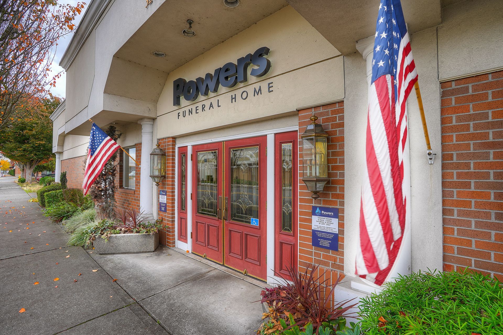 Potters grocery store entrance with red doors, brick facade, and large American flags on either side