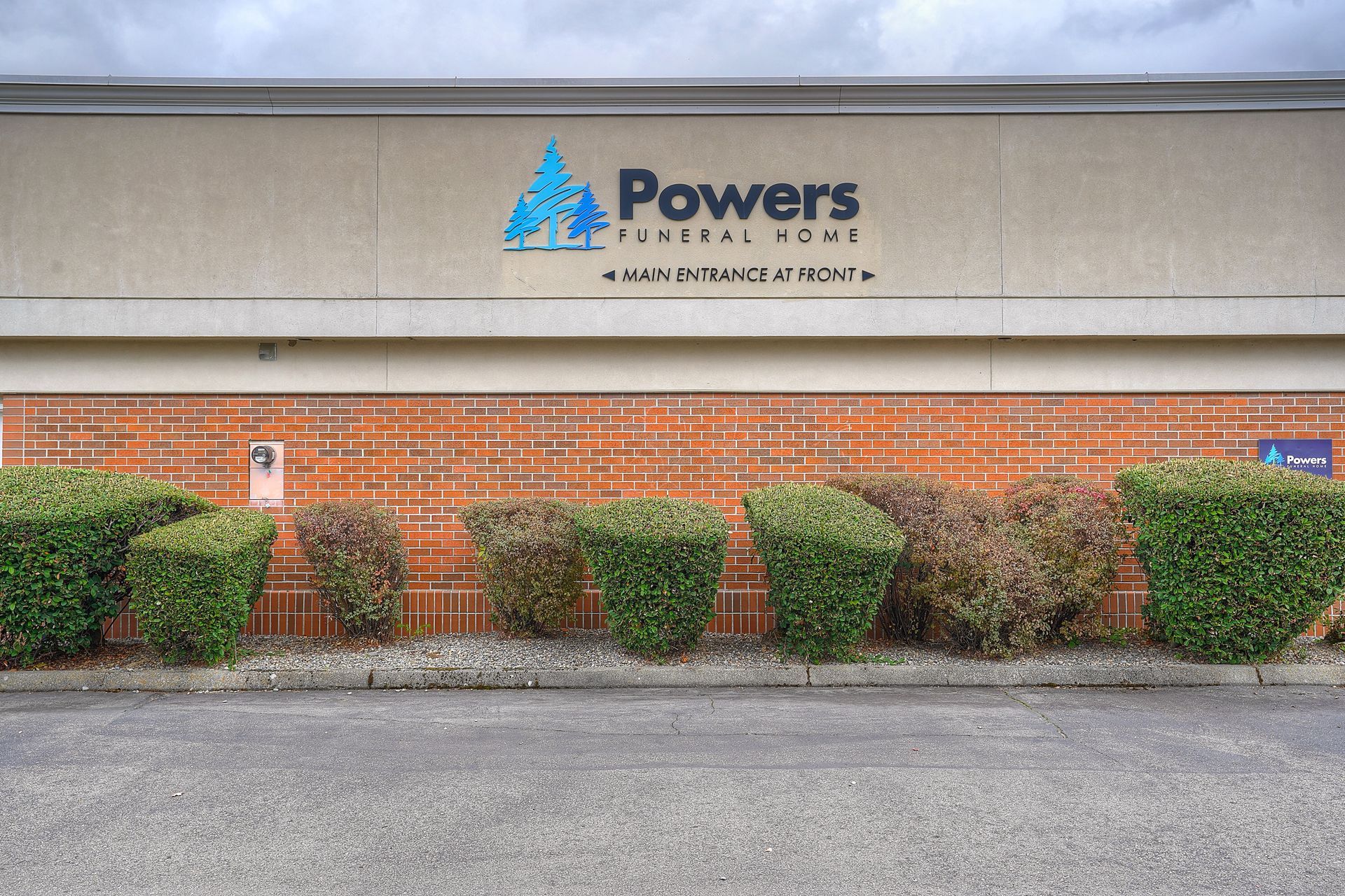Powers building sign above brick wall and trimmed shrubs along the front walkway