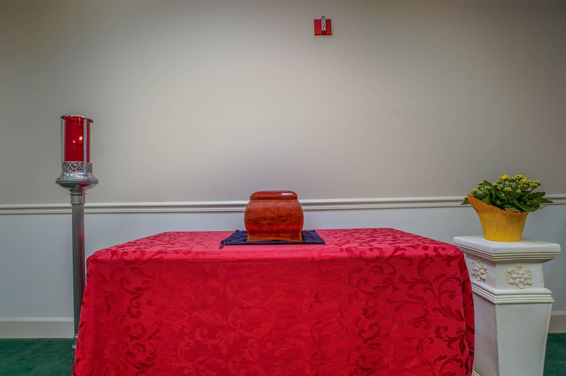 Altar with red cloth, candles, and flowers in a quiet chapel room