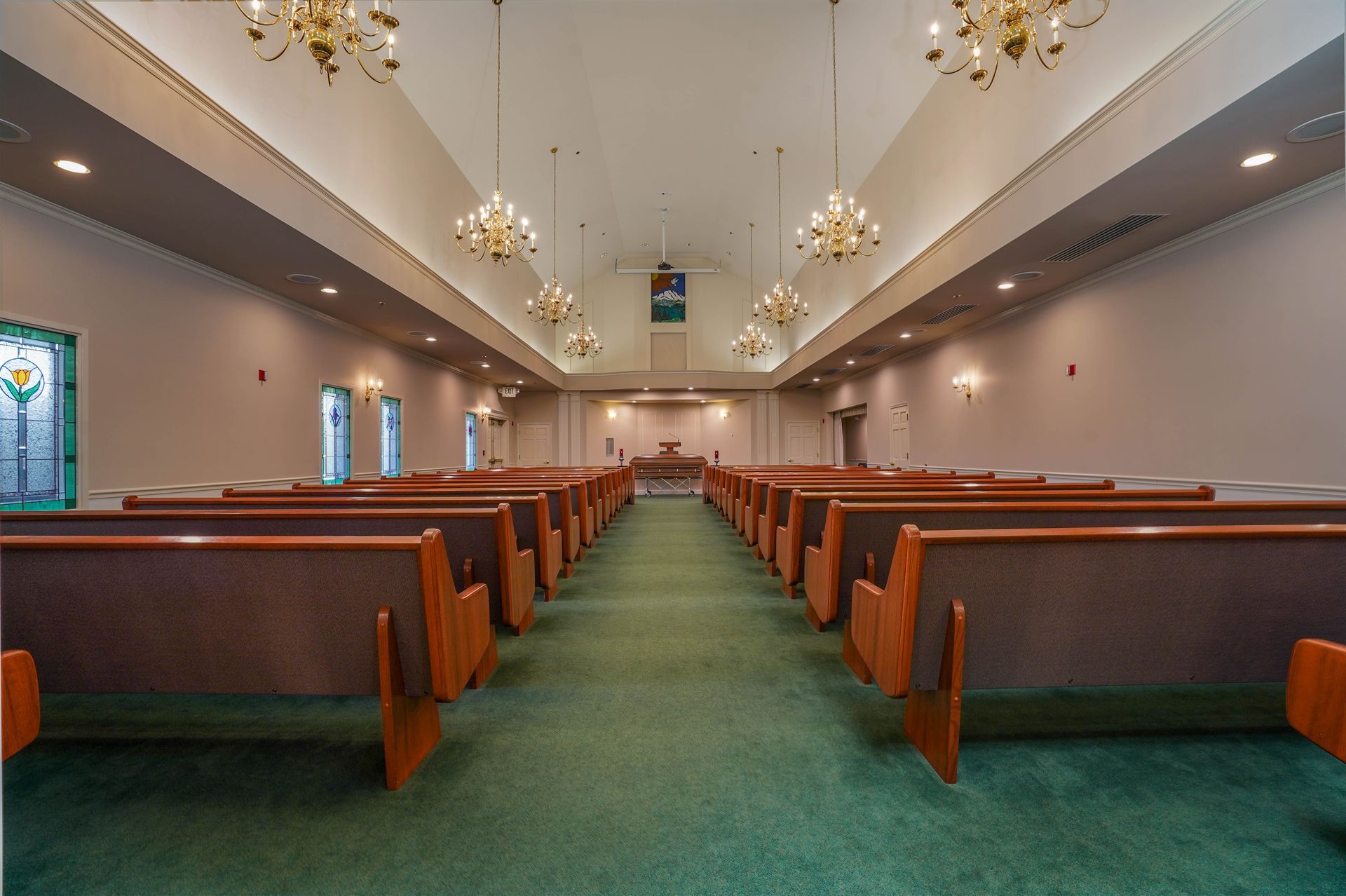 Empty church sanctuary with green carpet and wooden pews