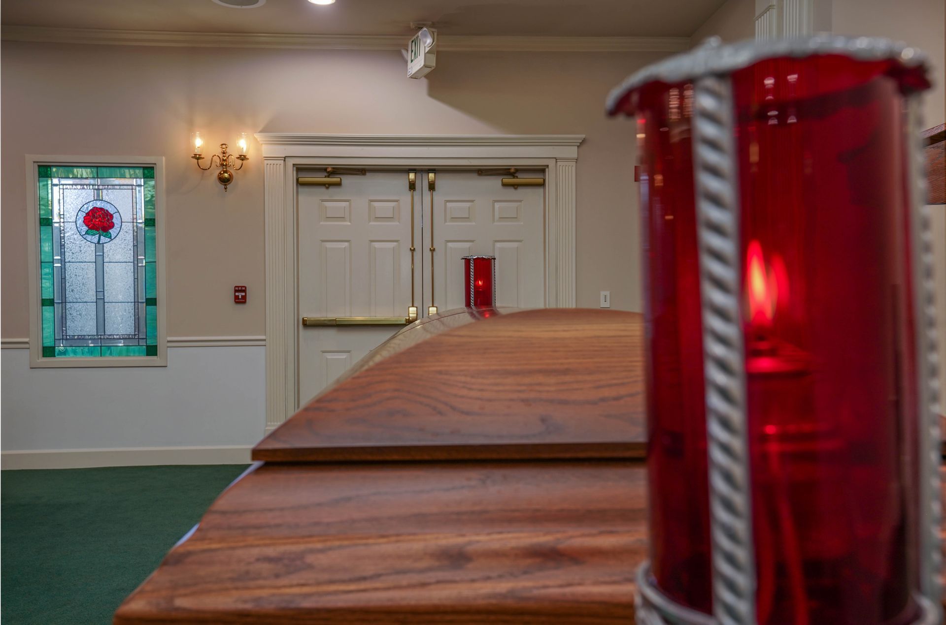 Church sanctuary with wooden coffin and red memorial candles near the front doors