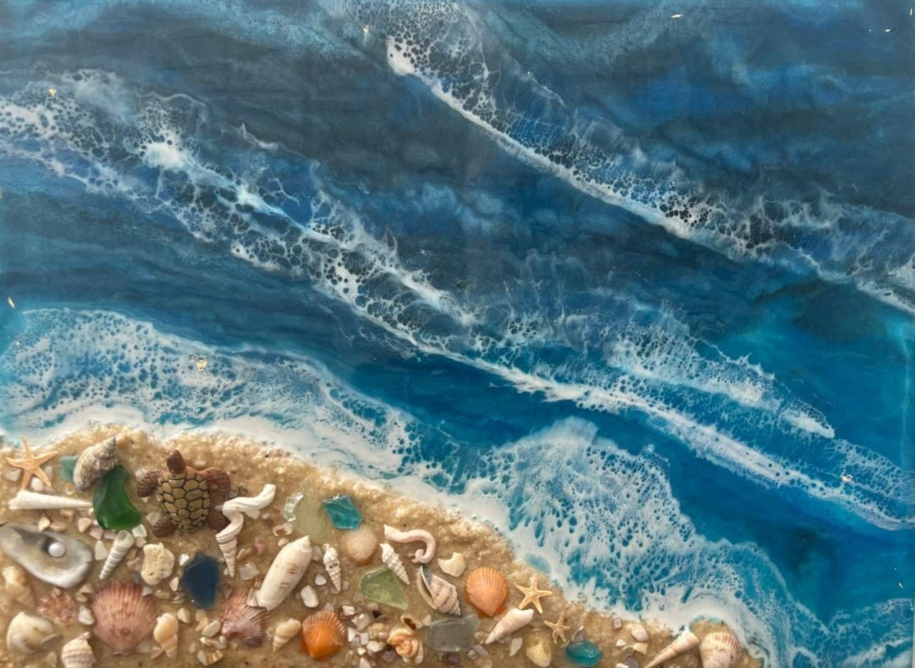 Blue ocean waves washing onto a sandy, shell-strewn beach with white foam