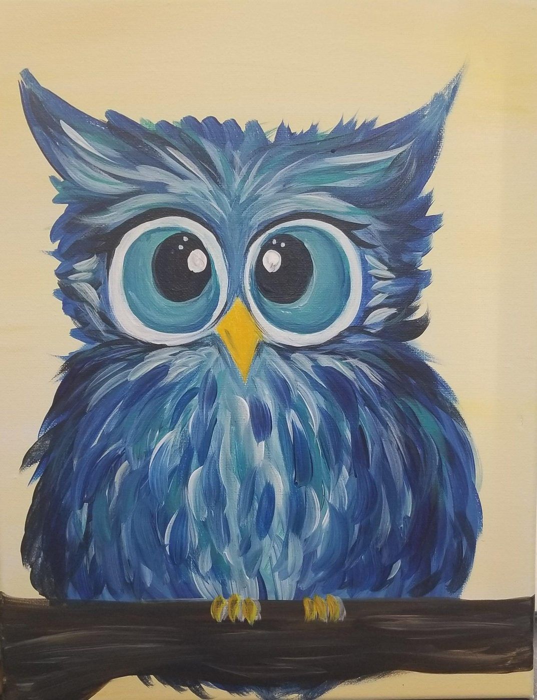Blue painted owl with big eyes perched on a dark branch against a light background