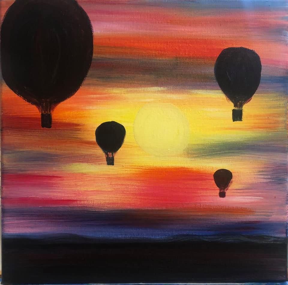 Silhouetted hot air balloons against a colorful sunrise sky over a dark horizon