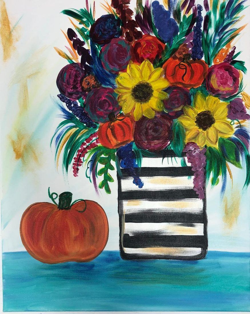 Pumpkin beside a striped vase of colorful flowers on a blue tabletop backdrop