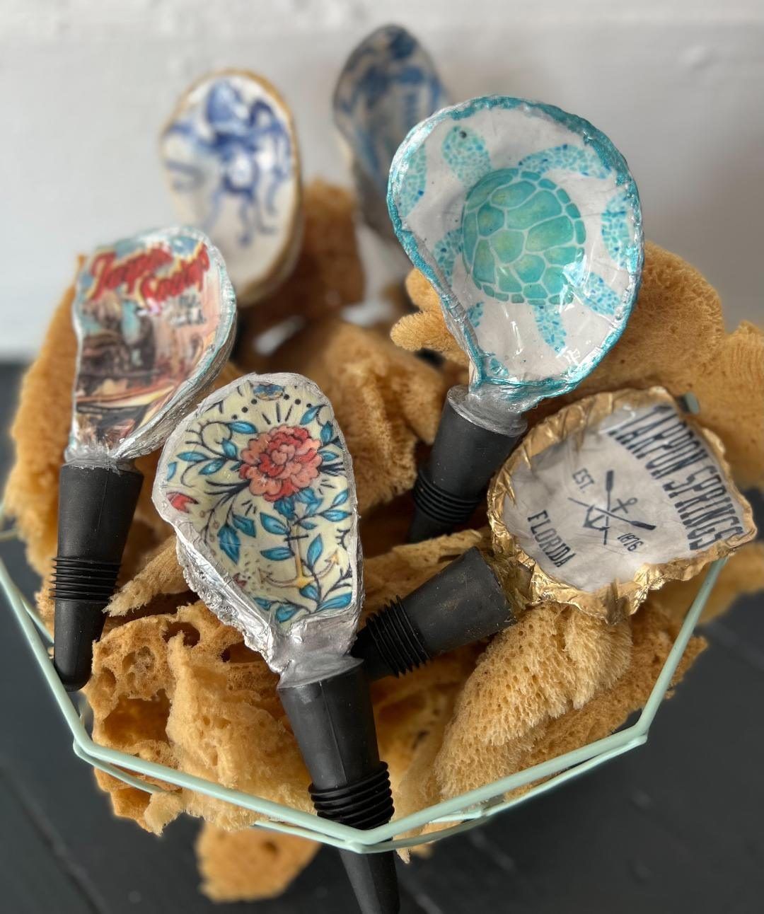 Decorative spoon handles in a glass bowl, each with floral and patterned tops