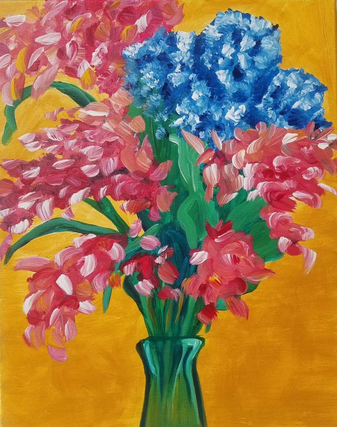 Colorful bouquet of pink and blue flowers in a green vase on a warm yellow background