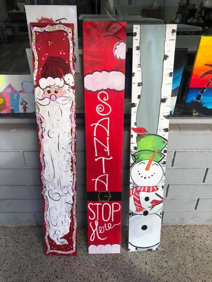 Christmas-themed wooden signs: Santa, snowman, and “SANTA STOP HERE” designs in red, white, and green