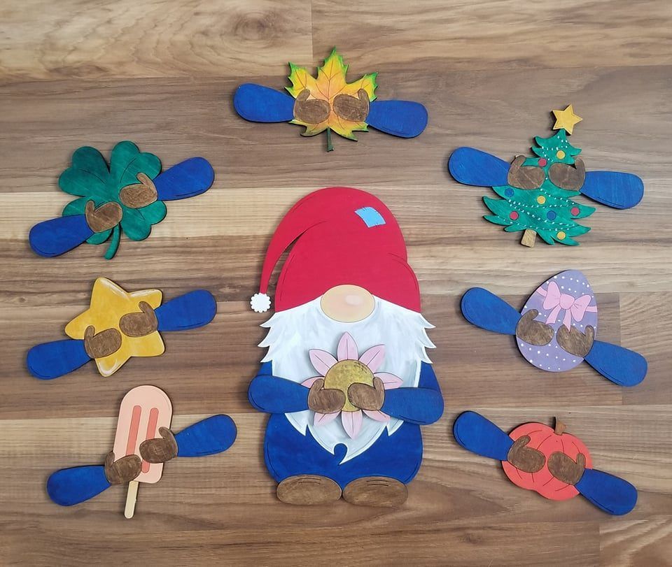 Colorful Christmas gnome surrounded by handmade holiday cutouts on a wooden table