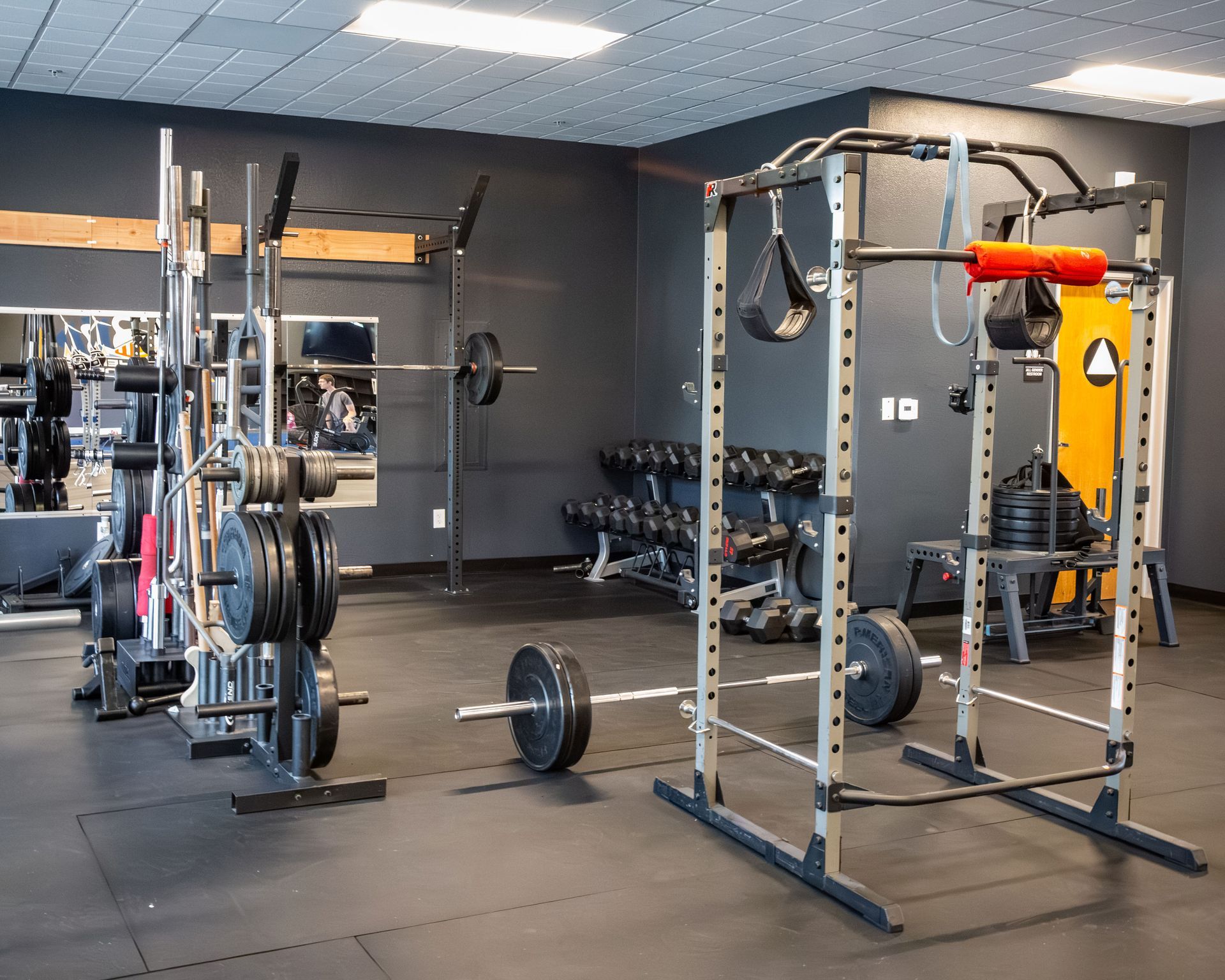 People exercising in a gym, doing planks and lifting barbells on a workout floor.