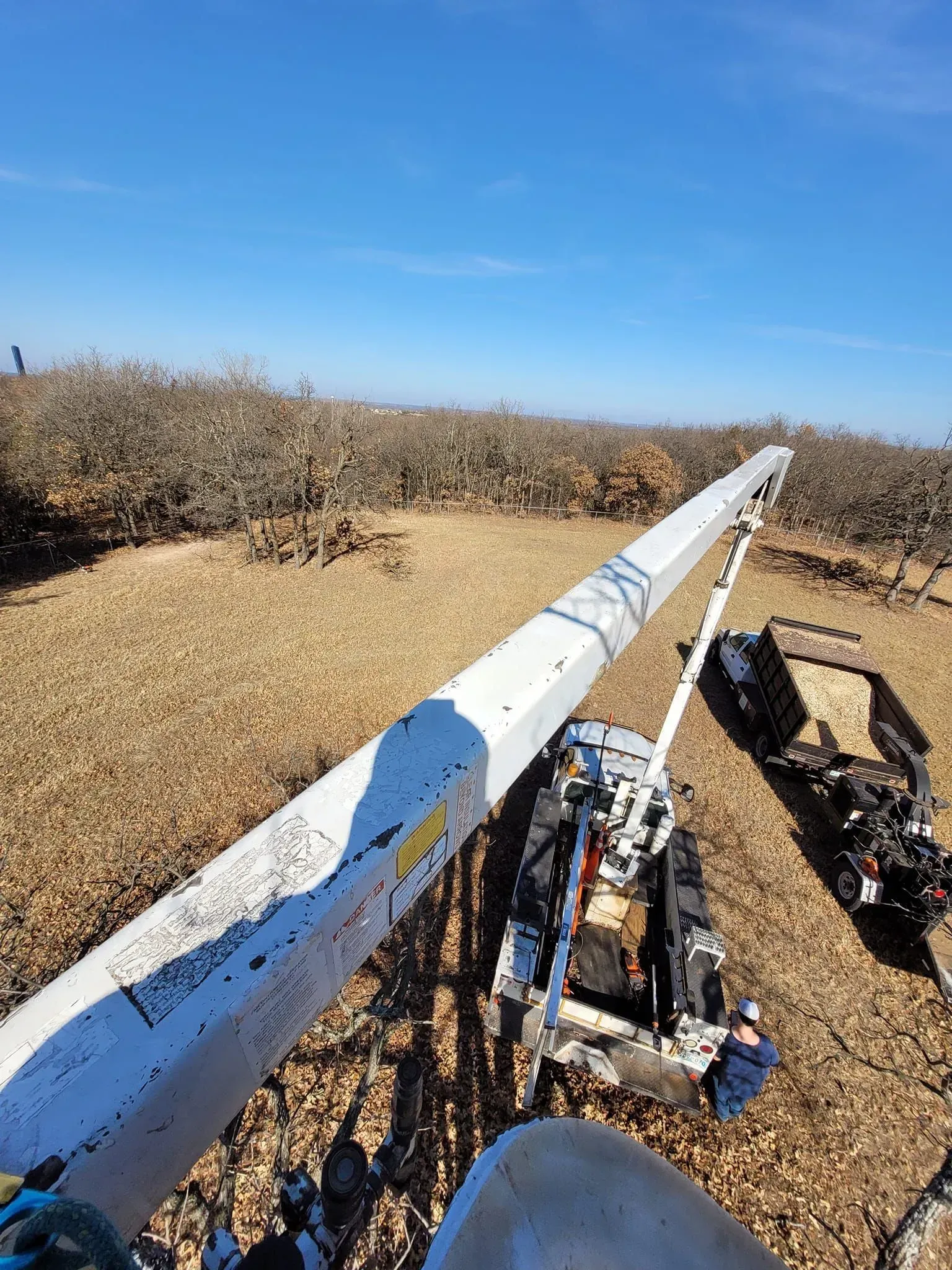 White barrier on a dry hillside under a clear blue sky, with equipment beside it on the right.