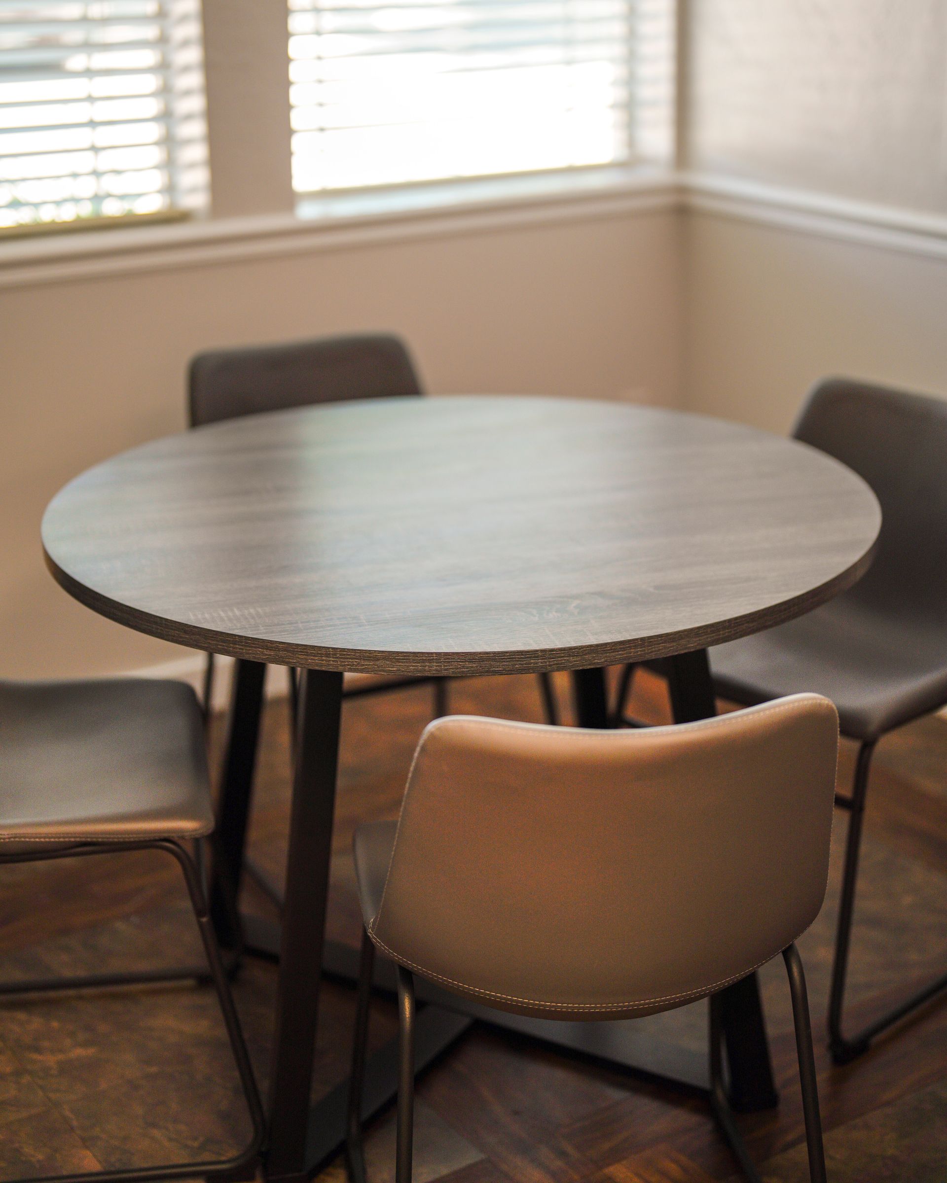 A round table with four chairs in front of a window