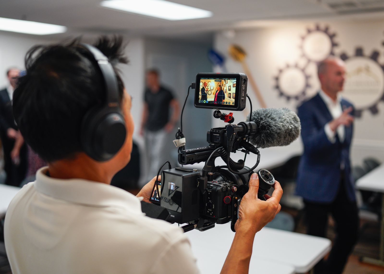 A man wearing headphones is recording a video with a camera.