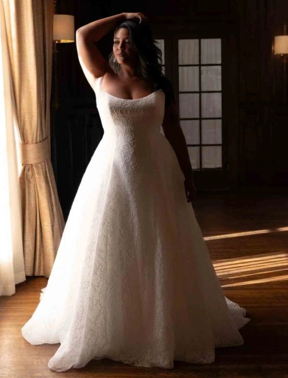 Woman in a white wedding dress posing indoors by a window