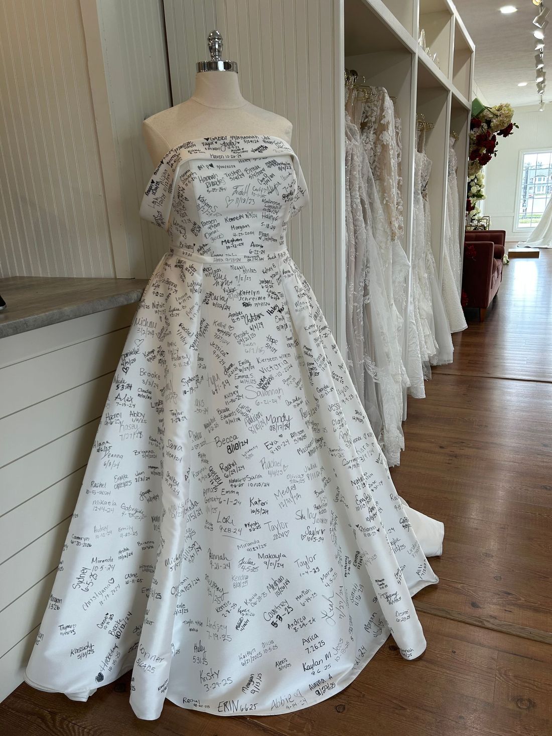 Strapless white wedding dress with gray floral print on a mannequin in a bridal shop.